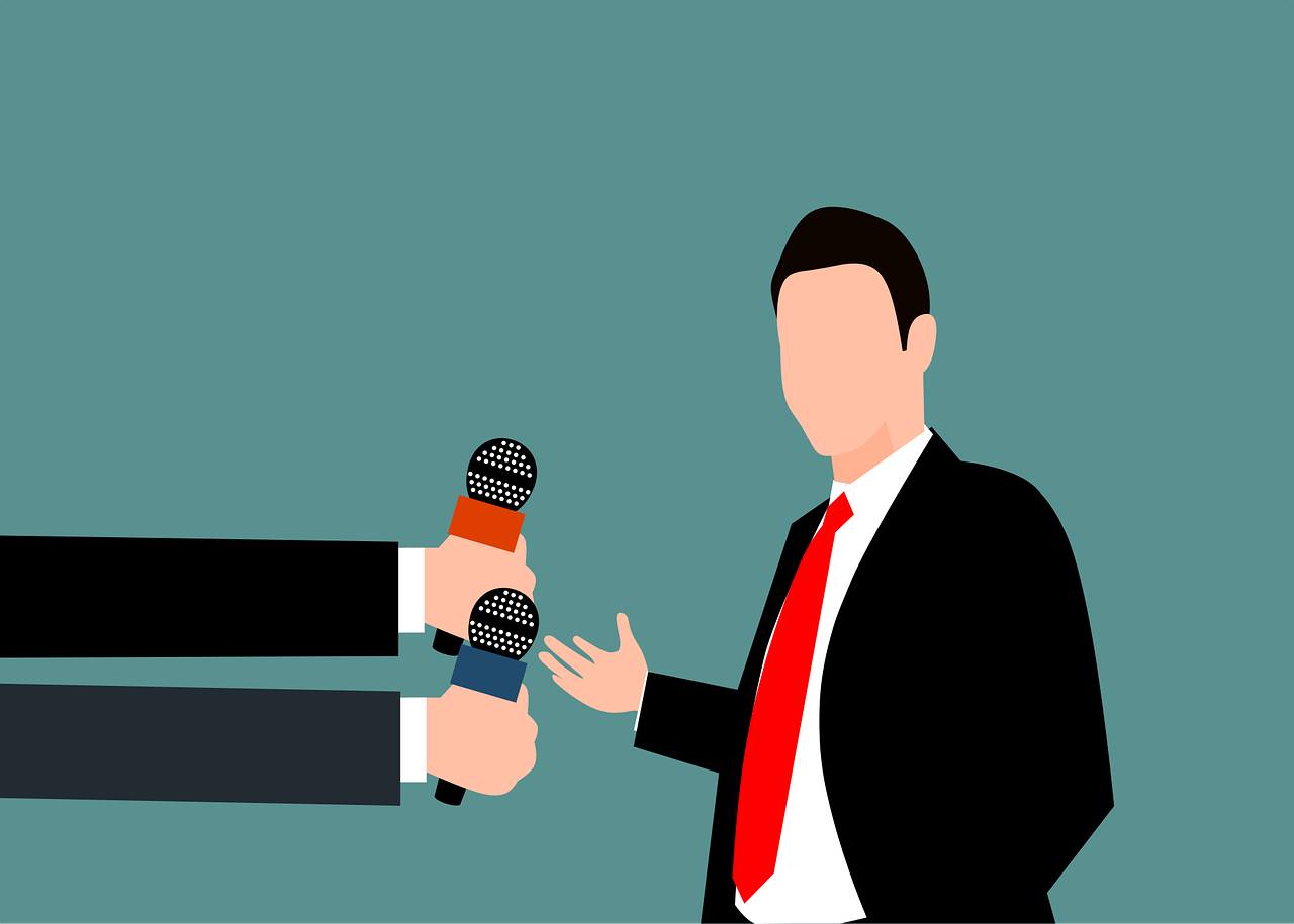 Un candidat interviewé par plusieurs journalistes tendant leurs micros
