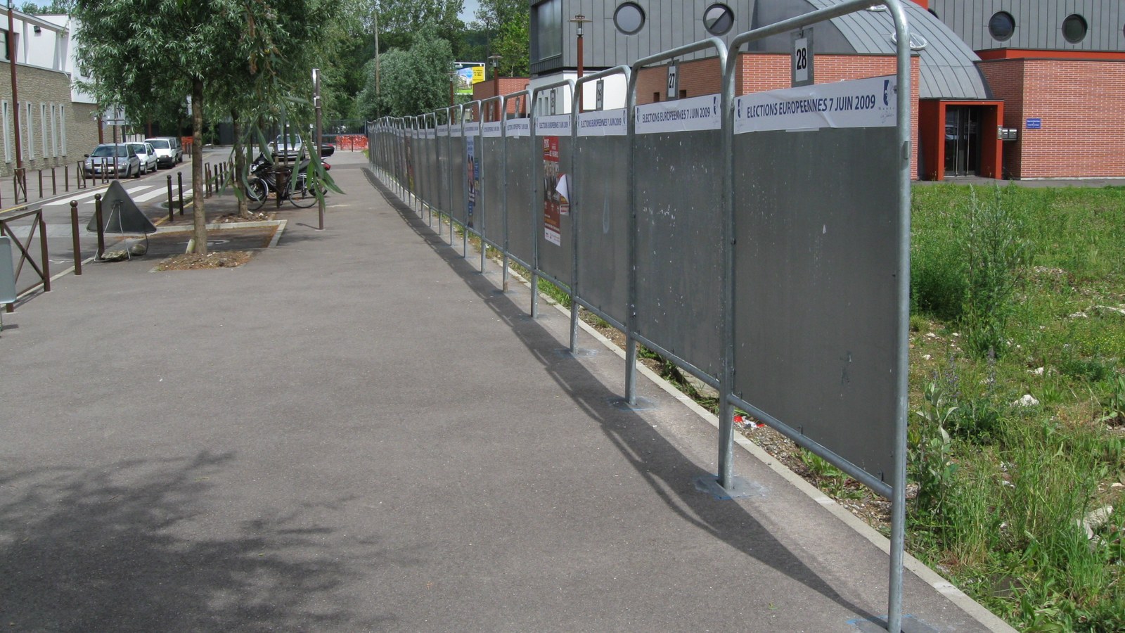Rangée de panneaux électoraux officiels numérotés le long d'un trottoir