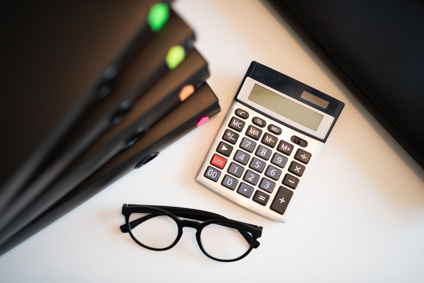 Calculatrice, lunettes et dossiers sur un bureau de travail